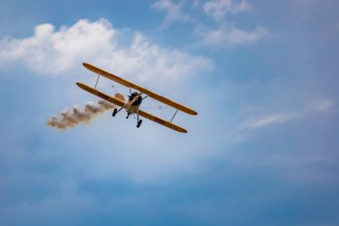 Leszno, Polonya - 16 Haziran 2023: Antidotum Airshow Leszno 2023 ve mavi bulutlu gökyüzünde sarı Boeing Stearman uçağı akrobatik gösterileri