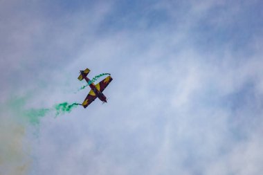 Leszno, Polonya - 16 Haziran 2023: Antidotum Airshow Leszno 2023 ve Marek Choim 'in bulutlu gökyüzünde uçan 330SC uçağında renkli dumanlarla dolu akrobatik gösterileri