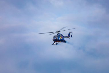Leszno, Polonya - 16 Haziran 2023: Antidotum Airshow Leszno 2023 ve hava bulutlu bir gökyüzünde Red Bull Bo 105 helikopteriyle uçan Felix Baumgartner 'ın dumanıyla dolu akrobatik gösterisi