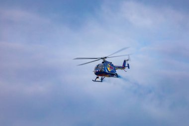 Leszno, Polonya - 16 Haziran 2023: Antidotum Airshow Leszno 2023 ve hava bulutlu bir gökyüzünde Red Bull Bo 105 helikopteriyle uçan Felix Baumgartner 'ın dumanıyla dolu akrobatik gösterisi