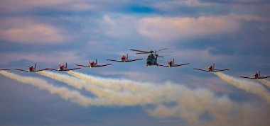 Leszno, Polonya - 16 Haziran 2023: Antidotum Airshow Leszno 2023 ve akrobatik, bulutlu bir gökyüzünde PC-7 uçak ekibi ve Super Puma ekran ekibi helikopteri dumanlarıyla dolu.