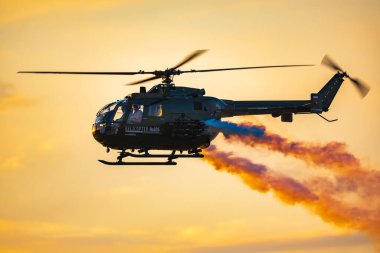 Leszno, Polonya - 16 Haziran 2023: Antidotum Airshow Leszno 2023 ve bulutlu gökyüzünde Bo 105 PL helikopter dumanı dolu akrobatik gösteriler