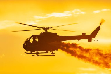 Leszno, Polonya - 16 Haziran 2023: Antidotum Airshow Leszno 2023 ve bulutlu gökyüzünde Bo 105 PL helikopter dumanı dolu akrobatik gösteriler