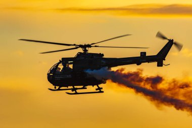 Leszno, Polonya - 16 Haziran 2023: Antidotum Airshow Leszno 2023 ve bulutlu gökyüzünde Bo 105 PL helikopter dumanı dolu akrobatik gösteriler