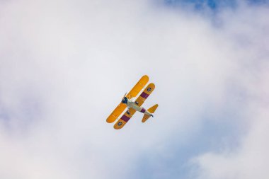 Leszno, Polonya - 17 Haziran 2023: Antidotum Airshow Leszno 2023 ve mavi bulutlu gökyüzünde sarı Boeing Stearman uçağı akrobatik gösterileri