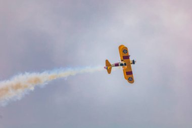 Leszno, Polonya - 17 Haziran 2023: Antidotum Airshow Leszno 2023 ve mavi bulutlu gökyüzünde sarı Boeing Stearman uçağı akrobatik gösterileri