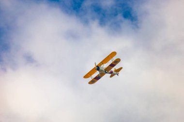 Leszno, Polonya - 17 Haziran 2023: Antidotum Airshow Leszno 2023 ve mavi bulutlu gökyüzünde sarı Boeing Stearman uçağı akrobatik gösterileri