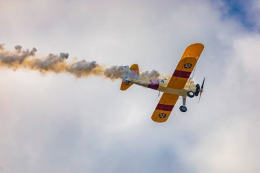 Leszno, Polonya - 17 Haziran 2023: Antidotum Airshow Leszno 2023 ve mavi bulutlu gökyüzünde sarı Boeing Stearman uçağı akrobatik gösterileri