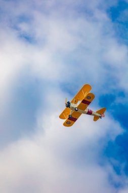 Leszno, Polonya - 17 Haziran 2023: Antidotum Airshow Leszno 2023 ve mavi bulutlu gökyüzünde sarı Boeing Stearman uçağı akrobatik gösterileri