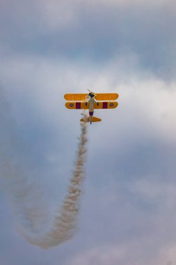 Leszno, Polonya - 17 Haziran 2023: Antidotum Airshow Leszno 2023 ve mavi bulutlu gökyüzünde sarı Boeing Stearman uçağı akrobatik gösterileri
