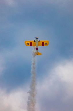 Leszno, Polonya - 17 Haziran 2023: Antidotum Airshow Leszno 2023 ve mavi bulutlu gökyüzünde sarı Boeing Stearman uçağı akrobatik gösterileri