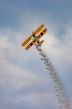 Leszno, Polonya - 17 Haziran 2023: Antidotum Airshow Leszno 2023 ve mavi bulutlu gökyüzünde sarı Boeing Stearman uçağı akrobatik gösterileri