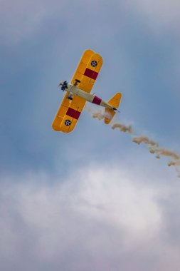 Leszno, Polonya - 17 Haziran 2023: Antidotum Airshow Leszno 2023 ve mavi bulutlu gökyüzünde sarı Boeing Stearman uçağı akrobatik gösterileri