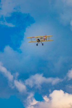 Leszno, Polonya - 17 Haziran 2023: Antidotum Airshow Leszno 2023 ve mavi bulutlu gökyüzünde sarı Boeing Stearman uçağı akrobatik gösterileri