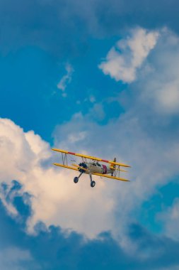 Leszno, Polonya - 17 Haziran 2023: Antidotum Airshow Leszno 2023 ve mavi bulutlu gökyüzünde sarı Boeing Stearman uçağı akrobatik gösterileri