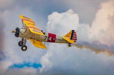 Leszno, Polonya - 17 Haziran 2023: Antidotum Airshow Leszno 2023 ve mavi bulutlu gökyüzünde sarı Boeing Stearman uçağı akrobatik gösterileri