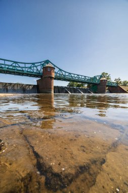 Wroclaw, Polonya - 4 Haziran 2023: Yürüyen turist ve bisikletçilerle dolu uzun Bartoszowicki köprüsü güneşli bir günde kurumuş nehirden görülen su seviyesi üzerinde