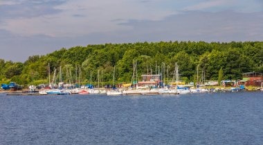 Smardzewice, Polonya - 9 Haziran 2023: Güneşli bir sabahta büyük göl kıyısında tekne ve feribot dolu küçük bir koy