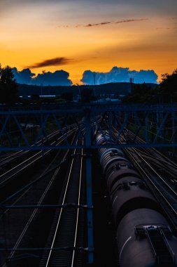 Güzel bir manzara bulutlu bir gün batımı güzel altın gökyüzü ve mavi bulutlar yüksek yaya köprüsünden görünüyor tren rayları üzerinde kargo treniyle istasyonda.