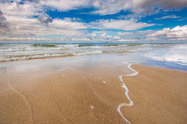 Kumlu sahil kıyıları ve bulutlu gökyüzü ile fırtınalı deniz manzarası