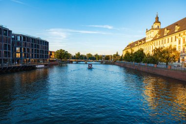 Wroclaw, Polonya - 15 Temmuz 2023: Wroclaw Üniversitesi ile günbatımında Pomorski Köprüsü 'nden görülen modern apartmanlar arasında Odra Nehri' nin güzel şehir manzarası