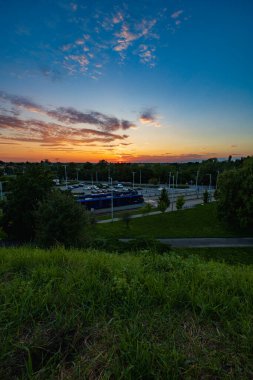 Wroclaw, Poland - August 23 2023: Beautiful cloudy sunset seen from Oporowskie hill over square with big tram depot with car parking