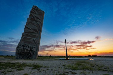 Wroclaw, Poland - August 23 2023: Beautiful big cross on top of of Oporowskie hill with graves around next to big monument to the Soldiers of the Polish Army at beautiful cloudy sunset