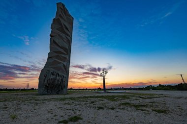 Wroclaw, Poland - August 23 2023: Beautiful big cross on top of of Oporowskie hill with graves around next to big monument to the Soldiers of the Polish Army at beautiful cloudy sunset