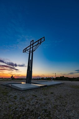 Wroclaw, Poland - August 23 2023: Beautiful big cross on top of of Oporowskie hill with graves around at beautiful cloudy sunset