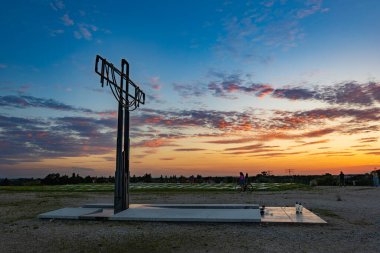 Wroclaw, Poland - August 23 2023: Beautiful big cross on top of of Oporowskie hill with graves around at beautiful cloudy sunset