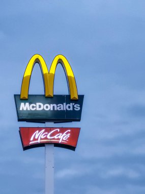Wroclaw, Poland - August 8 2023: Big and high sign with McDonald's logo on top and McCafe logo below at cloudy afternoon