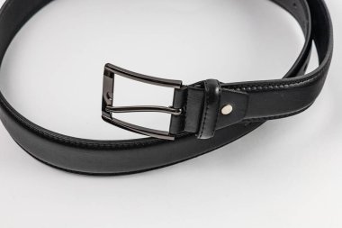 Uzun ve geniş siyah deri kemer, birkaç küçük delik ve büyük metal toka.