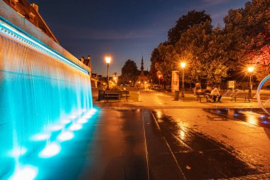 Gdansk, Polonya - 7 Eylül 2023: Güzel Hevelius çeşmesi etraftaki renkli ışıklarla aydınlatılmış ve karanlık öğleden sonra etrafa su sıçratılmış