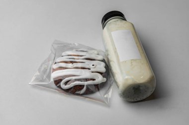 Bir şişe beyaz ve sağlıklı milkshake yanında büyük çikolatalı kurabiye, krema ve gözler.