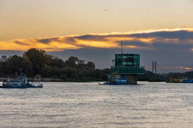 Varşova, Polonya - 15 Ekim 2023: Altın bulutlu güzel bulutlu gün doğumu ve Pinsk Flotilla Bulvarı 'ndan soğuk bir sabah görülen uzun Vistula nehri üzerinde yükselen güneş