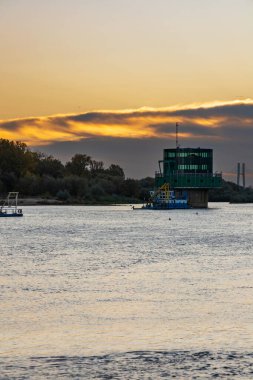 Varşova, Polonya - 15 Ekim 2023: Altın bulutlu güzel bulutlu gün doğumu ve Pinsk Flotilla Bulvarı 'ndan soğuk bir sabah görülen uzun Vistula nehri üzerinde yükselen güneş