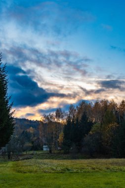 Sonbaharda altın ve yeşil ağaçlarla dolu güzel dağ manzarası ve birkaç küçük bulutla açık mavi gökyüzü.