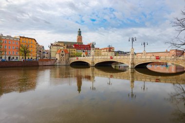 Wroclaw, Polonya - 6 Nisan 2024: Yenilenmiş Pomorski Köprüsü Odra Nehri 'nin sakin sularına yansıyarak şehrin ufuk çizgisinin resimli bir manzarasını oluşturdu