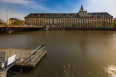 Wroclaw, Polonya - 7 Nisan 2024: Wroclaw 'ın görkemli üniversitesi Odra Nehri boyunca dimdik ayakta duruyor.