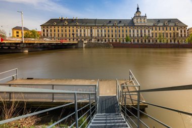 Wroclaw, Polonya - 7 Nisan 2024: Wroclaw 'ın görkemli üniversitesi Odra Nehri boyunca dimdik ayakta duruyor.