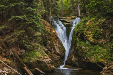 Beautiful giant Szklarka waterfall with giant rocks around and green surroundings clipart