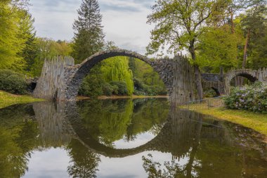 Kromlau, Almanya - 3 Mayıs 2024: Rododendron ve Azalea Bahçesi, kemerli köprüler, göletler, tarihi bir konut ve sayısız rhododendron ile iyi korunan 19. yüzyıl parkı