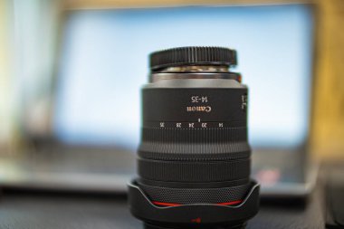 Wroclaw, Poland - July 3 2024: Canon mirrorless camera lens Canon RF 14-35mm F4L IS USM for modern cameras standing upside down on wooden table clipart