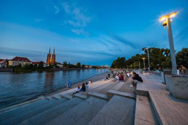 Wroclaw, Polonya - 25 Temmuz 2024: Katedral manzaralı Wroclaw Riverside gezinti alanında Akşam Rahatlığı