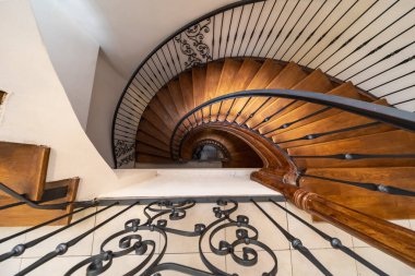 Tahta basamaklar, metal korkuluklar ve açık renkli döşemeler içeren sarmal bir merdiven manzarası mimari ya da iç mimari tasarım teması için mükemmel.