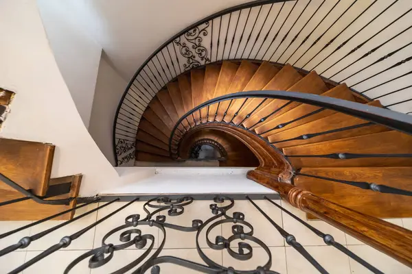 Tahta basamaklar, metal korkuluklar ve açık renkli döşemeler içeren sarmal bir merdiven manzarası mimari ya da iç mimari tasarım teması için mükemmel.