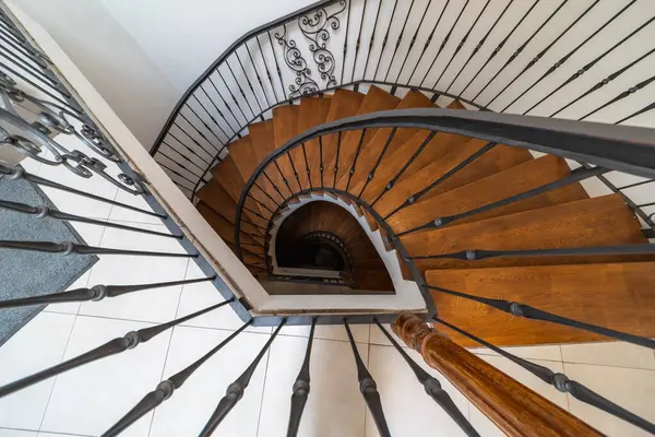 Tahta basamaklar, metal korkuluklar ve açık renkli döşemeler içeren sarmal bir merdiven manzarası mimari ya da iç mimari tasarım teması için mükemmel.