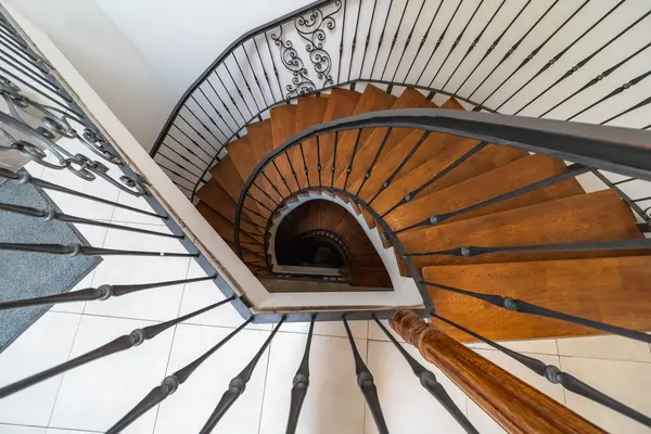 Tahta basamaklar, metal korkuluklar ve açık renkli döşemeler içeren sarmal bir merdiven manzarası mimari ya da iç mimari tasarım teması için mükemmel.