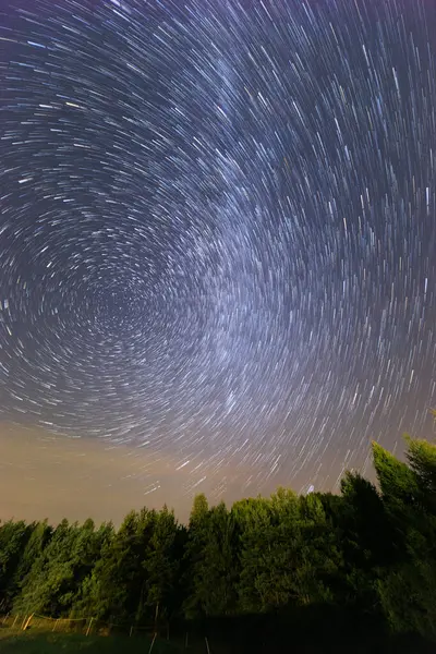 Karanlık gece gökyüzünde güzel yıldız izleri bazı tarlalar ve yüksek ağaçların siluetleri üzerinde Samanyolu ile hareket eden bulutlar ve uçan Perseidler