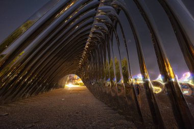 Wroclaw, Polonya - 24 Ağustos 2024: Wroclaw 'daki Daliowa Adası' nda gece aydınlatılmış Nawa heykeli, yıldızlı bir gökyüzü altında şehir ışıklarını yansıtan modern bir sanat kurulumu